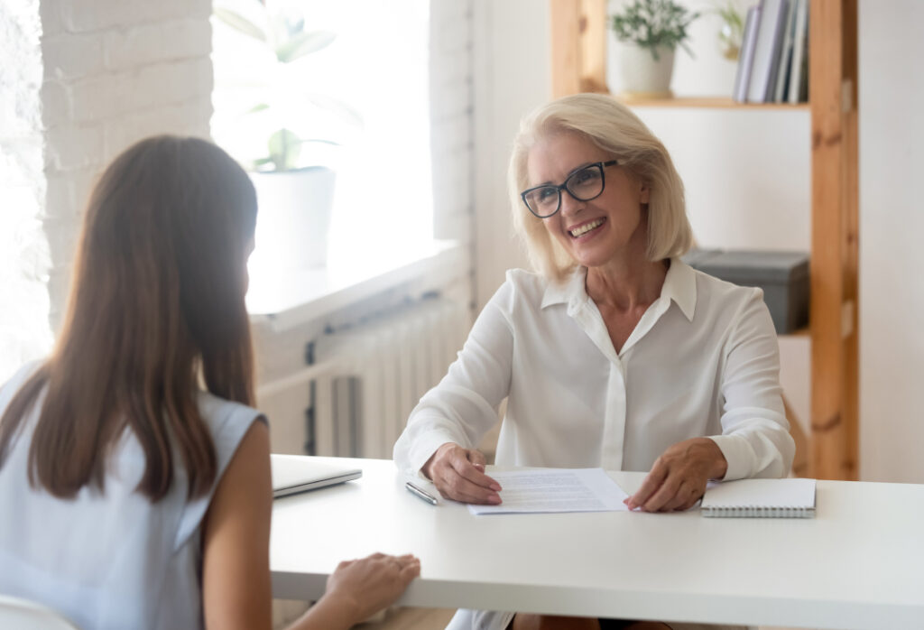 Two women having a professional discussion at a bright office table.