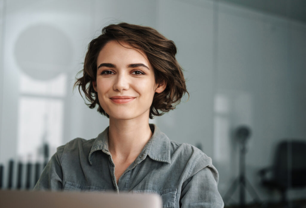 Smiling employee in a modern office setting promoting workplace assistance services.