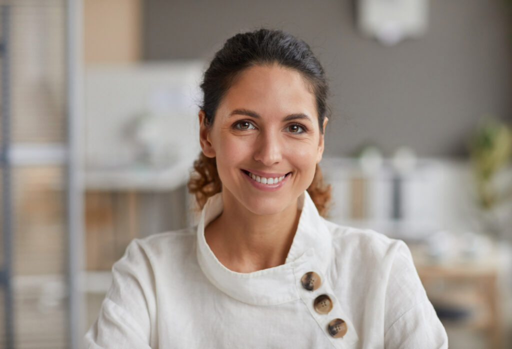 Smiling woman in casual attire in a modern office workspace.