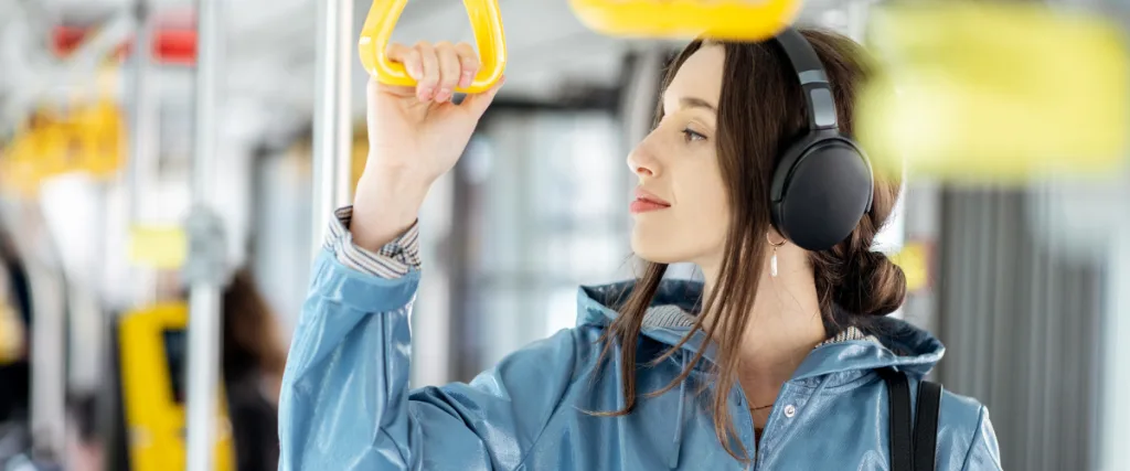 A woman in a blue coat listens to music on a bus commute.