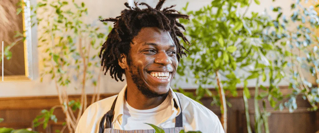 Employee smiling joyfully in a lush office environment surrounded by greenery.