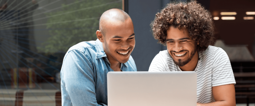 Two colleagues happily collaborating on a project with a laptop.